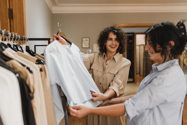 Two Ojai residents in collared shirts admire a high quality white t-shirt in an upscale clothing boutique